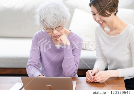 若い女性にパソコン操作を習うシニア女性	 123529645