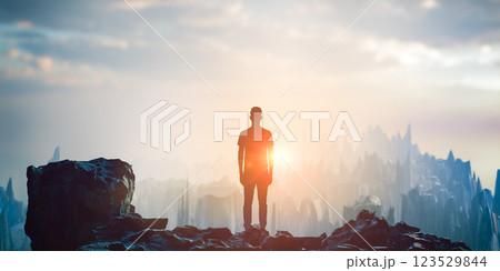 silhouette of sad man standing on ruins after war with destroyed landscape and dramatic sky in background under fading sunlight 123529844
