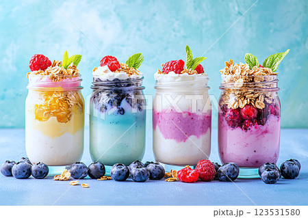 On the go breakfast mason jars layered with yogurt, berries and granola in bright colors 123531580