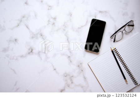 Flat lay top view notebook and pencil with mobile phone and glasses on white color office desk 123532124