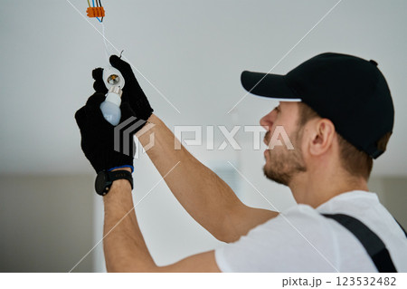 Electrician installing light bulb in new apartment during renovation Electrician installing light bulb in new apartment during renovation 123532482