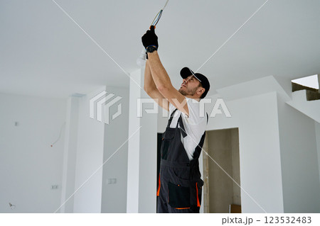Electrician installing light bulb in new apartment during renovation Electrician installing light bulb in new apartment during renovation 123532483