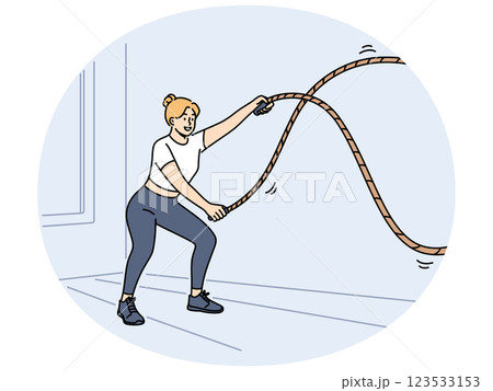 Woman doing fitness using battle rope training at sport center to lose weight or build muscles 123533153