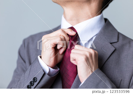 グレーのスーツを着てネクタイを直すミドル男性ビジネスマン グレーのスーツを着てネクタイを直すミドル男性ビジネスマン 123533596