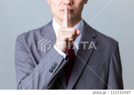 グレーのスーツを着て口に指を当てるミドル男性ビジネスマン 123533597