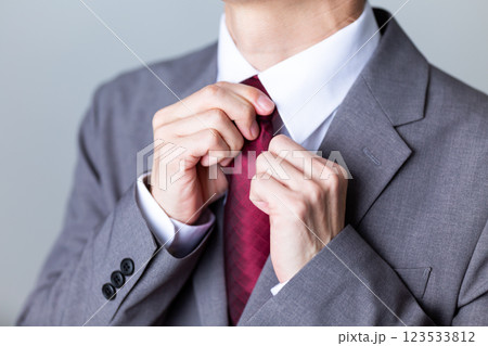 グレーのスーツを着てネクタイを直すミドル男性ビジネスマン グレーのスーツを着てネクタイを直すミドル男性ビジネスマン 123533812