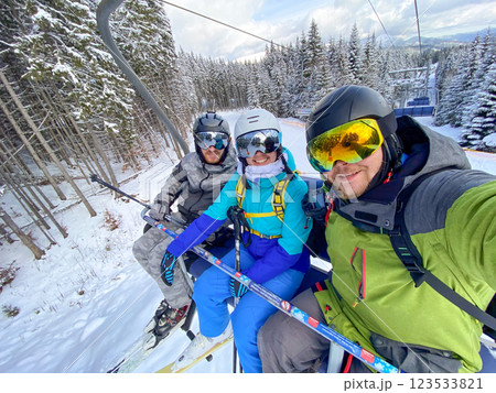 Friends Enjoying Ski Lift in Snowy Mountains 123533821