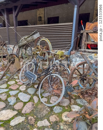 Vintage Bicycles and Rusty Wheels Scattered on Cobblestone Yard, Rustic Outdoor . High quality photo 123533966