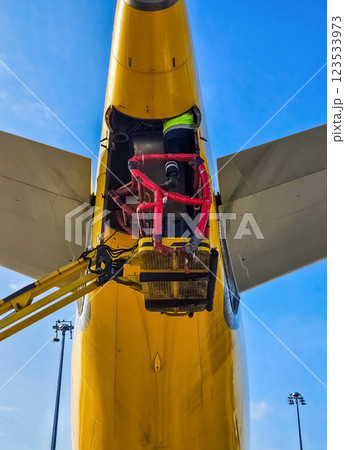 Aircraft maintenance work under the yellow fuselage with hydraulic lift. High quality photo 123533973