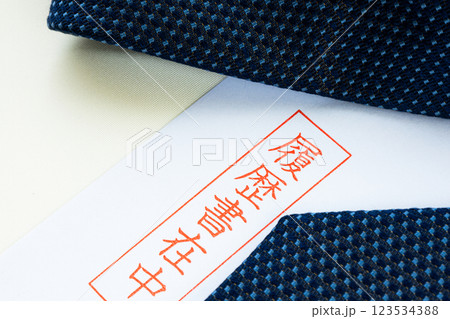 再就職に向けて履歴書を手書きで書きネクタイを用意しているイメージ 再就職に向けて履歴書を手書きで書きネクタイを用意しているイメージ 123534388