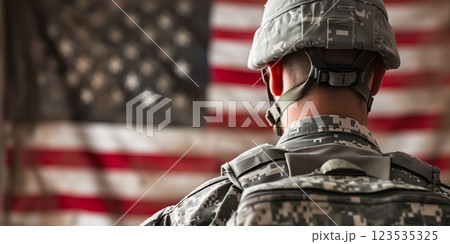 Soldier in camouflage uniform standing with the American flag in the background, symbolizing patriotism, duty, and service to the nation 123535325