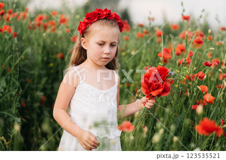 Ukrainian Beautiful girl in field of poppies and wheat. outdoor portrait in poppies. girl collecting poppies and cornflower in summer field. Ukrainian Beautiful girl in field of poppies and wheat. outdoor portrait in poppies. girl collecting poppies and cornflower in summer field. 123535521