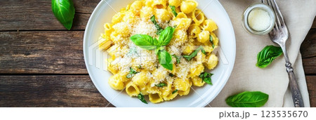 Rustic pasta dish topped with fresh basil and Parmesan served on a wooden table 123535670