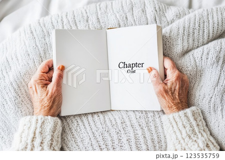 Older woman opens journal to begin new story with soft lighting and cozy atmosphere 123535759