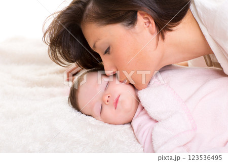 Baby girl and mother kissing her lying happy on white Baby girl and mother kissing her lying happy on white 123536495