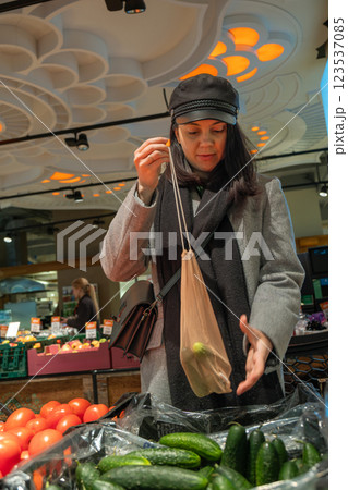 Woman Shopping for Cucumbers with Reusable Bag 123537085