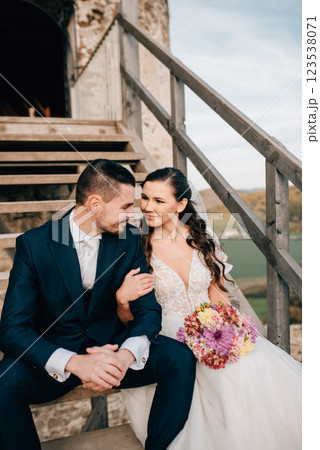 Portrait of beautiful wedding couple, sitting on wooden stairs. 123538071