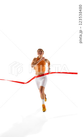 Front view of motivated female athlete dashing towards finish line, red ribbon breaking, expression of satisfaction and determination Front view of motivated female athlete dashing towards finish line, red ribbon breaking, expression of satisfaction and determination 123538480