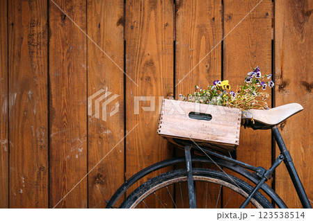 Vintage bicycle with wooden crate filled with flowers against rustic wooden wall, showcasing eco-friendly urban gardening and sustainable decor 123538514