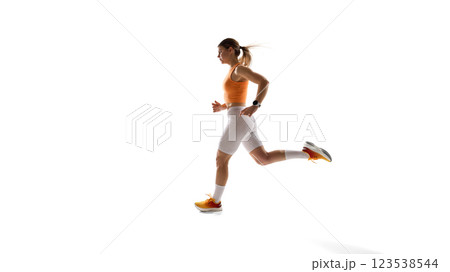 Young sportive woman in orange top and white leggings in motion, running against white studio background. Training 123538544
