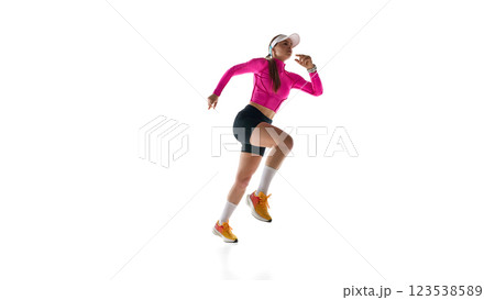 Energetic young woman, professional runner sprinting forward, focusing on strength and speed against white studio background. Energetic young woman, professional runner sprinting forward, focusing on strength and speed against white studio background. 123538589
