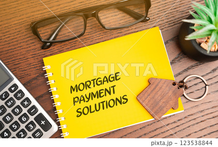 Mortgage payment solutions inscription in notebook. Real estate and finance concept, investment in loan and housing. Glasses, calculator and house keychain Mortgage payment solutions inscription in notebook. Real estate and finance concept, investment in loan and housing. Glasses, calculator and house keychain 123538844