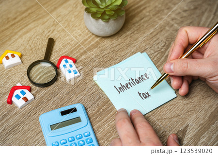 Inheritance Tax IHT is a tax on the estate (property, money, and possessions) of a person who has passed away. Real estate and finance. Notes, calculator and houses on a table 123539020