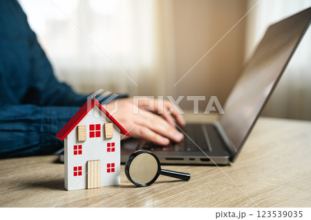 The concept of searching for housing via the Internet. Find an apartment for rent online. Property valuation and realtor services. House and magnifying glass and man with laptop. 123539035