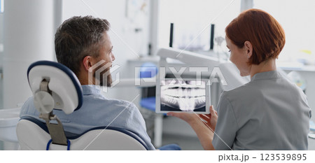 Female dentist showing x-ray to patient in dental clinic during anual check-up. 123539895