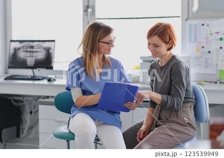Patient talking with her female dentis during annual check up in dental clinic. 123539949