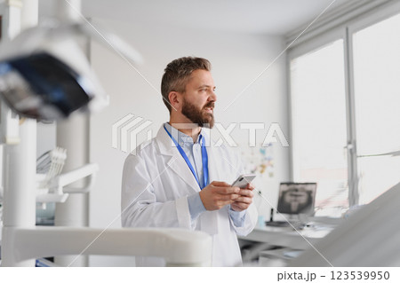 Portrait of handsome doctor in doctors office make phone call with patient. 123539950