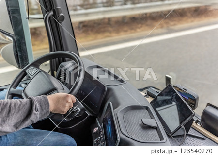 View of part of the driver's body in the cab of a moving truck. 123540270