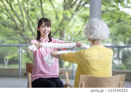 タオル体操をするシニア女性と介護スタッフ 123540283