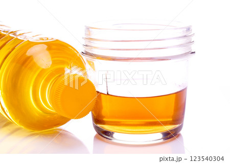 Selective focus of yellow plastic oil bottle with white cup provided, isolated white shadow 123540304