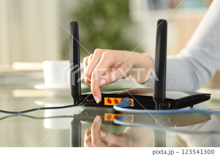 Woman hand reseting or turning on modem at home 123541300