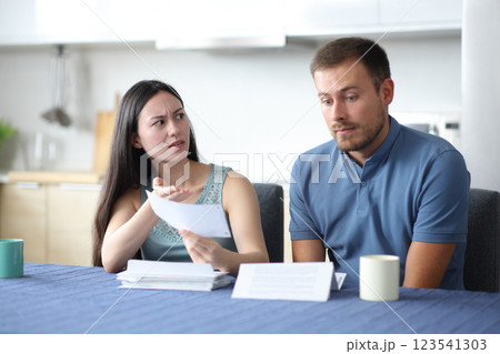 Woman scolding her partner showing problematic invoice Woman scolding her partner showing problematic invoice 123541303