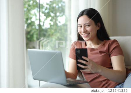 Happy asian woman posing with laptop and phone at home Happy asian woman posing with laptop and phone at home 123541323