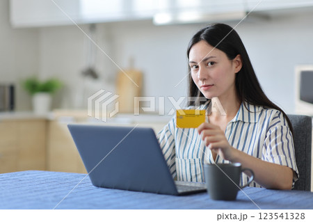 Serious asian woman paying online looking at you Serious asian woman paying online looking at you 123541328