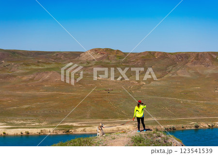 girl in a sports uniform with a dog in the mountains. woman with a husky on background of the steppe girl in a sports uniform with a dog in the mountains. woman with a husky on background of the steppe 123541539