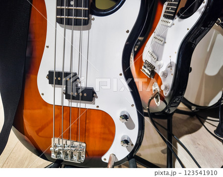 Guitars displayed on a stand in a music studio showcasing a bass guitar and an electric guitar during a daytime session 123541910
