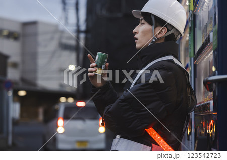 缶コーヒーを飲む作業着の男性 123542723