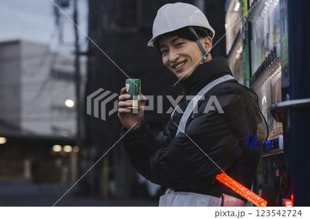 缶コーヒーを飲む作業着の男性 123542724
