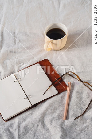 Open Journal with Pen on White Blanket, Next to Coffee Mug and Eyeglasses. 123542995