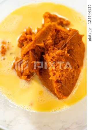 A close-up view of expertly blended ingredients in a large mixing bowl for a mouthwatering homemade pumpkin bundt cake. 123544139