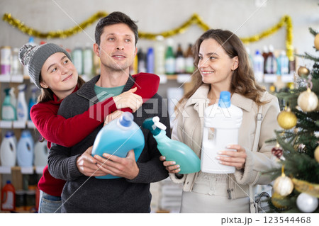 Couple man and woman with daughter choosing detergent and spray in decorated store 123544468