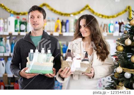 Couple choosing gift sets with self-care products at Christmas decorated store 123544518
