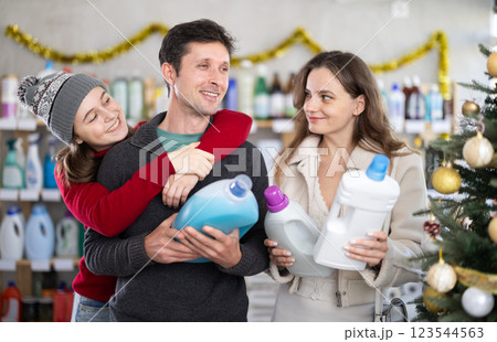 Couple man and woman with daughter choosing detergent in decorated store 123544563