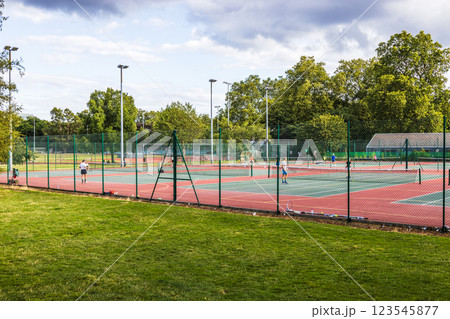 Sunny Outdoor Tennis Courts with Players and in a Public Park 123545877