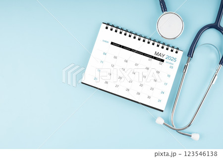 May 2025 desk calendar and stethoscope on blue, Position with copy space. 123546138
