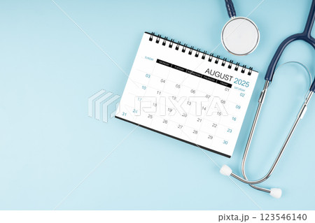 August 2025 desk calendar and stethoscope on blue, Position with copy space. August 2025 desk calendar and stethoscope on blue, Position with copy space. 123546140